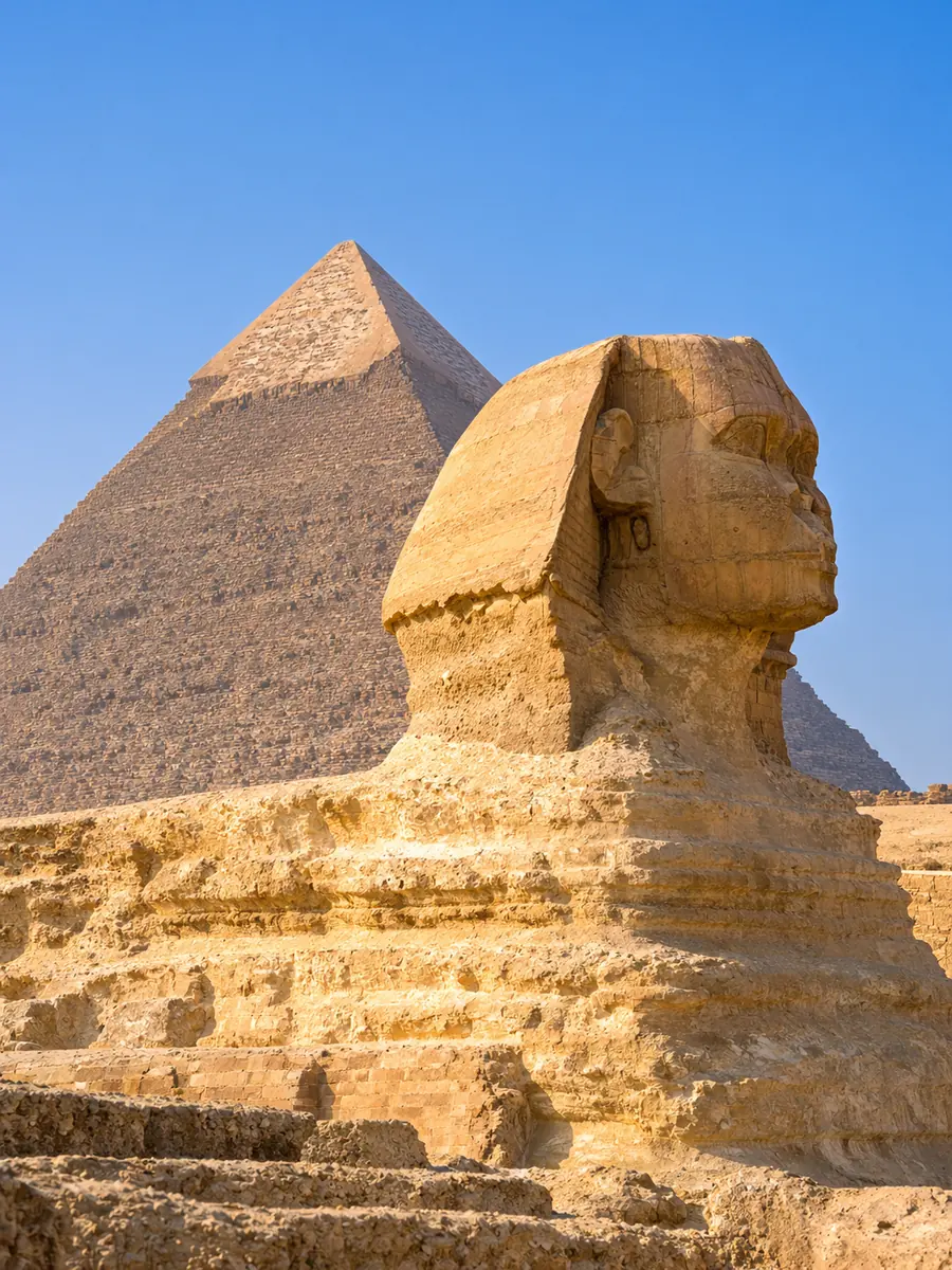 تمثال أبو الهول في الجيزة من الجانب في ضوء الصباح الدافئ، وهرم خفرع يرتفع خلفه تحت سماء زرقاء