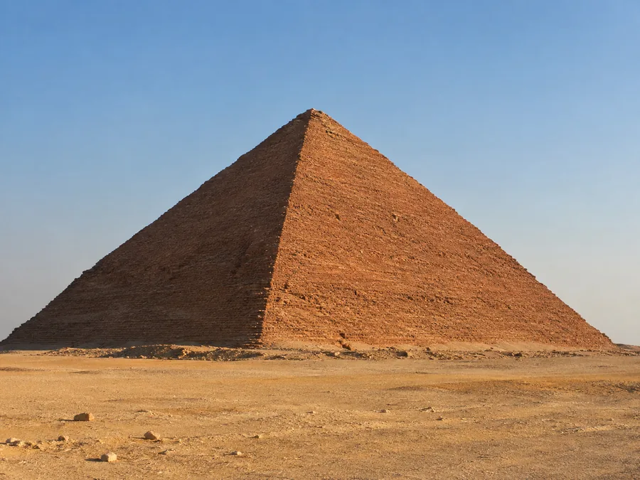 الهرم الأحمر في دهشور بجوانبه الملساء المائلة إلى الحمرة في ضوء العصر، والصحراء الخالية من حوله